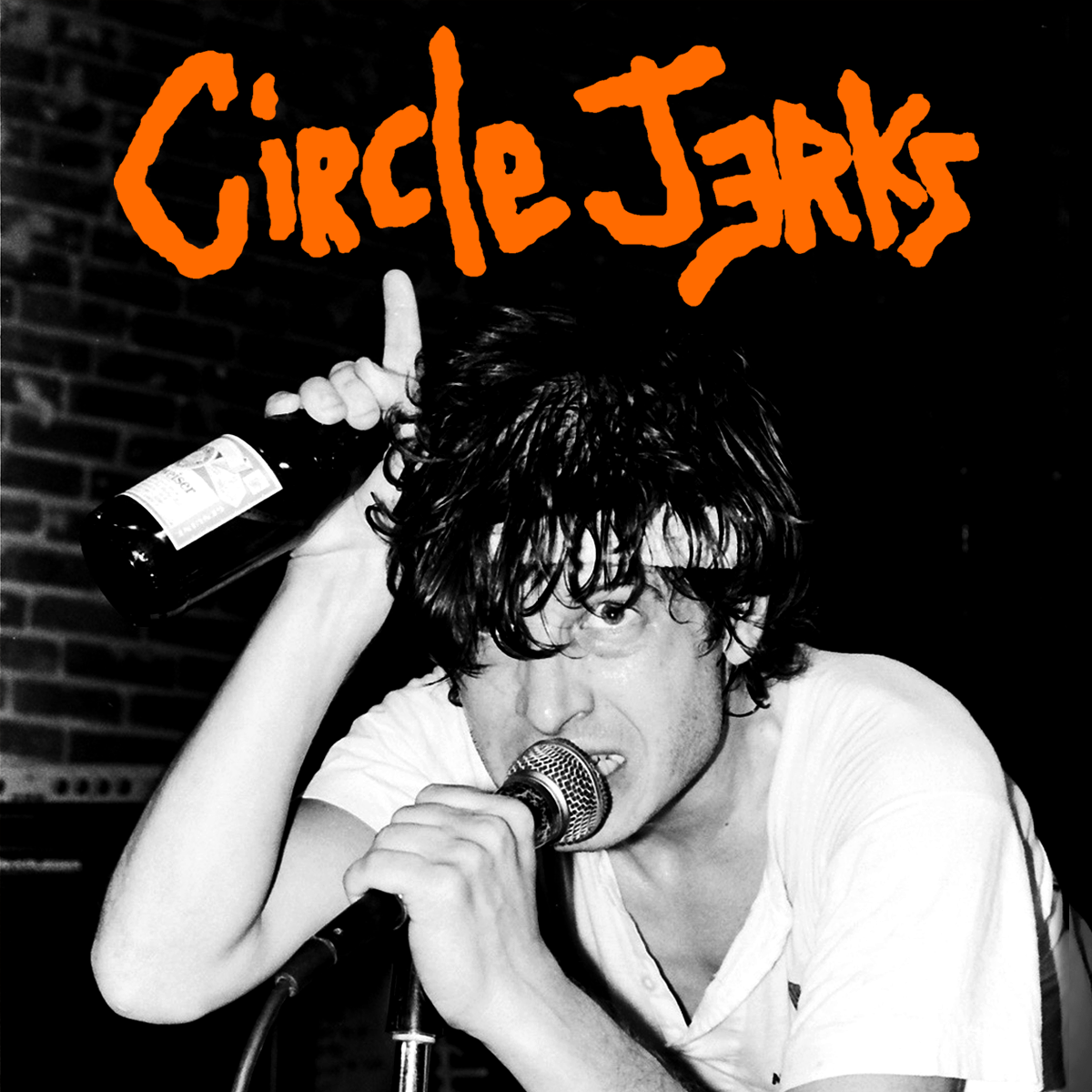 Black-and-white photo of a sweaty man holding a bottle and singing into a microphone, with Circle Jerks in bold orange, graffiti-style text above him.