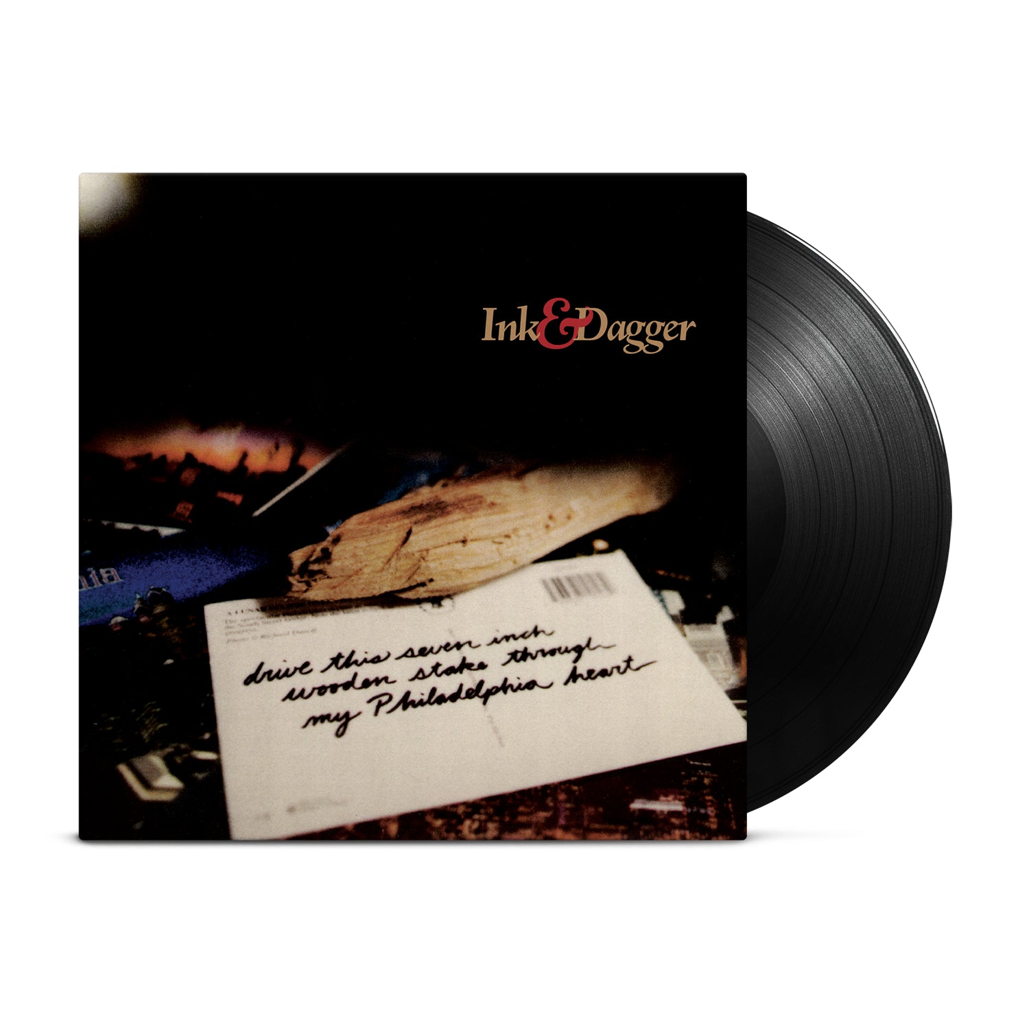 A black vinyl record partially out of its sleeve. The cover, by Ink & Dagger, features a blurred envelope with handwritten text and the band name in the top right, referencing their release "Drive This Seven Inch Wooden Stake Through My Philadelphia Heart.