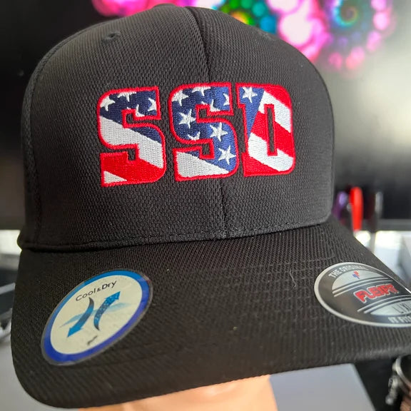 The SS Decontrol Flexfit Baseball Hat in black features SSD logo embroidery with a stars and stripes American flag design. Two brim stickers read Cool & Dry and FLEXFIT.