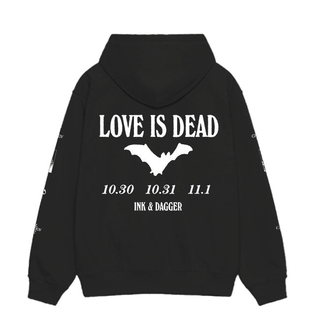 A black Ink & Dagger hoodie featuring "LOVE IS DEAD" in bold white letters, a bat graphic below, and the dates 10.30 10.31 11.1 above INK & DAGGER on the back, printed on premium Independent Trading Co. apparel.