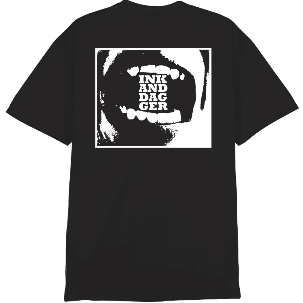 A black Ink & Dagger Comfort Colors T-shirt with a white square graphic of an open mouth and "INK AND DAGGER" on the teeth. Available for presale; shipping begins 12/12/25.