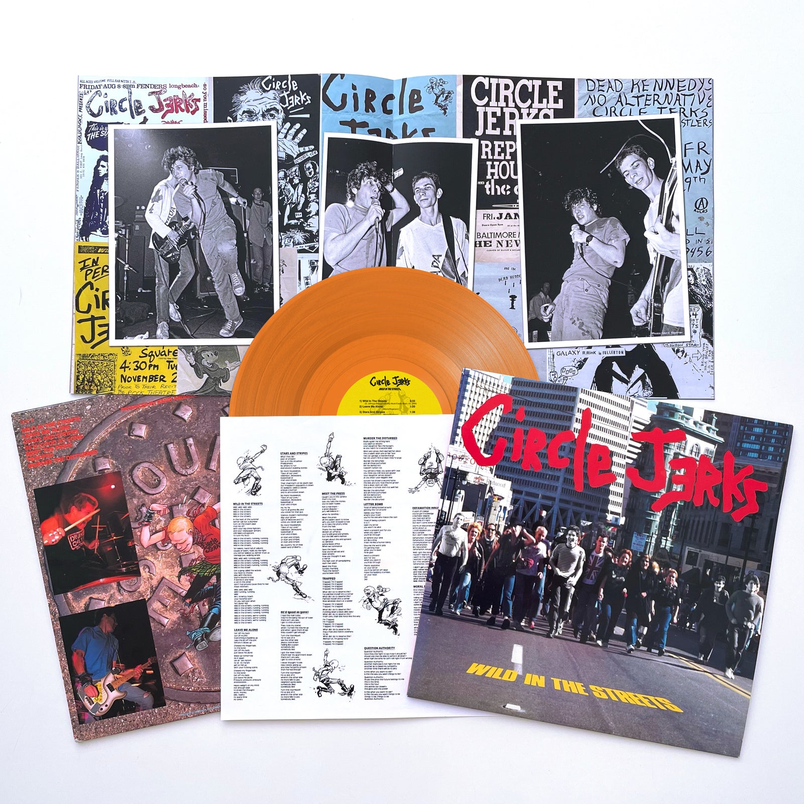 The image shows a Circle Jerks vinyl record with an orange-golden disc and an album cover depicting a crowd running on a city street, featuring the bands name in red and Wild In The Streets in yellow text.