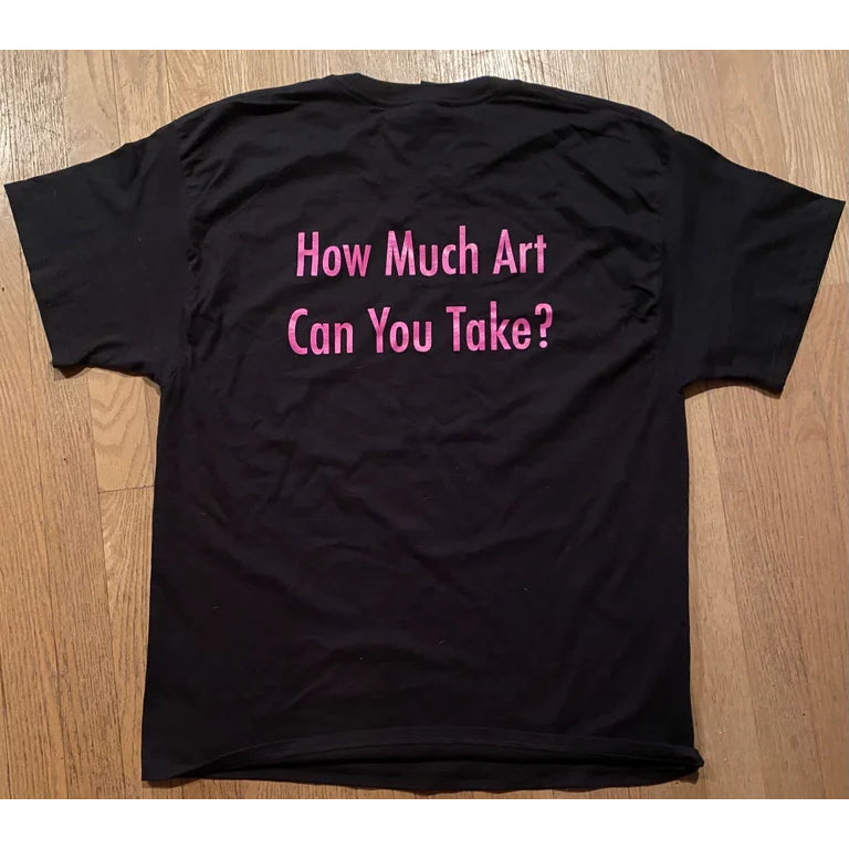 A black SS Decontrol tee is laid flat on a wooden floor, displaying large SSD lettering in purple outline centered on the chest.