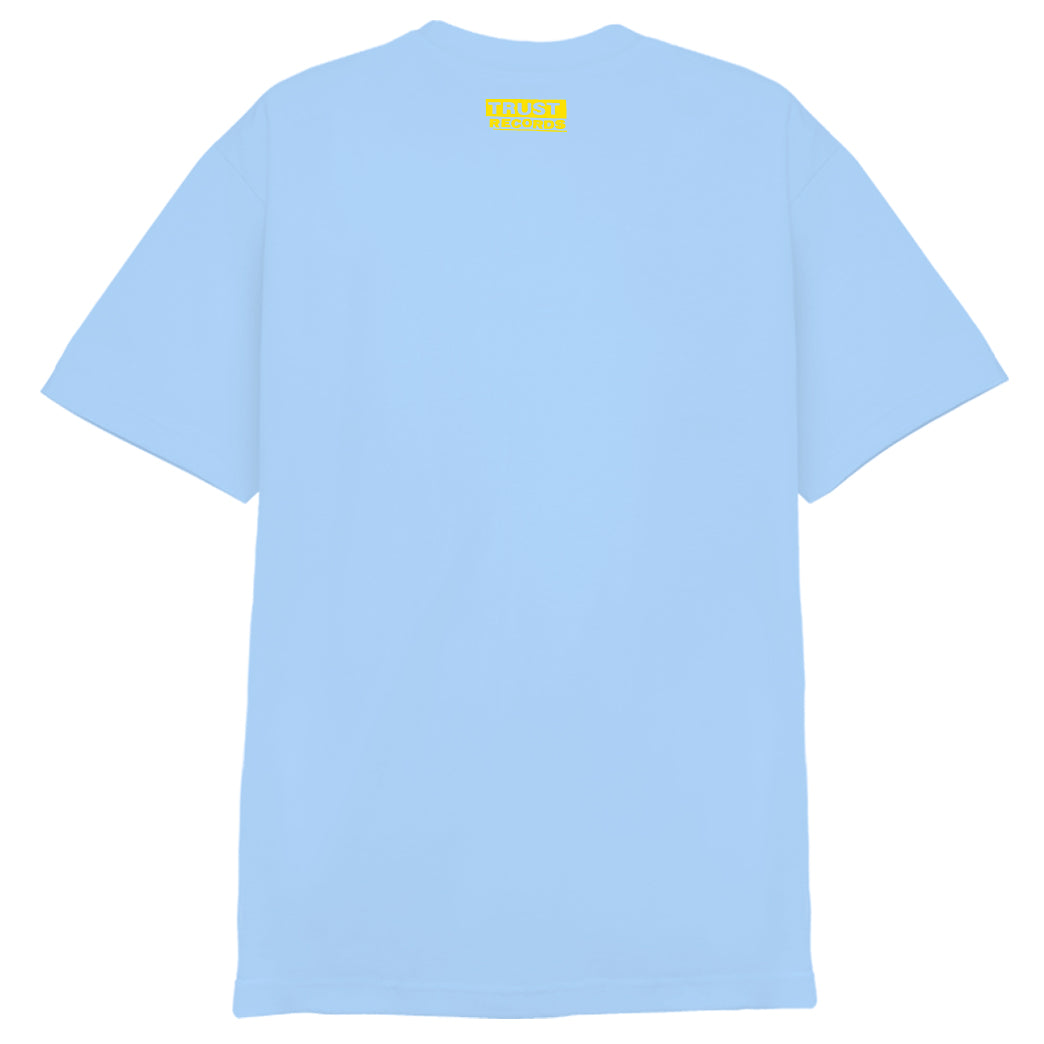 A plain light blue 7 Seconds T-shirt shown from the back, featuring a small yellow TRUST YOURSELF label near the neckline. Made from 100% cotton for comfort and durability.