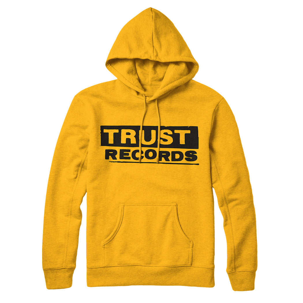 A yellow Trust Records pullover hoodie with a front pocket and drawstrings. Bold black text reads TRUST RECORDS on the chest, with TRUST in a black rectangle for a true streetwear style.