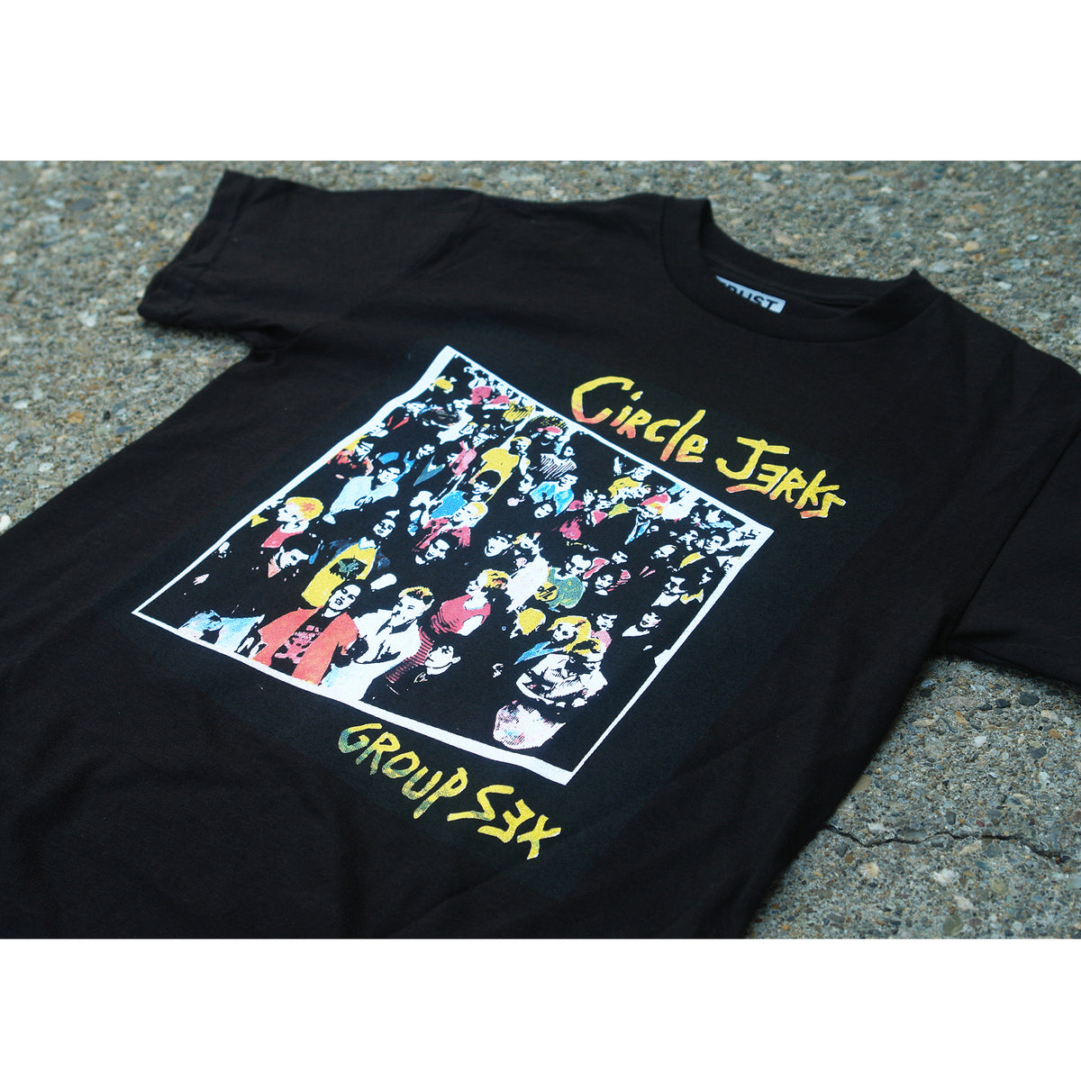 A black Circle Jerks T-shirt made of 100% cotton features a vibrant crowd graphic, "Circle Jerks" on top, and "Group Sex" below, all silkscreened and laid flat on a gray concrete surface.
