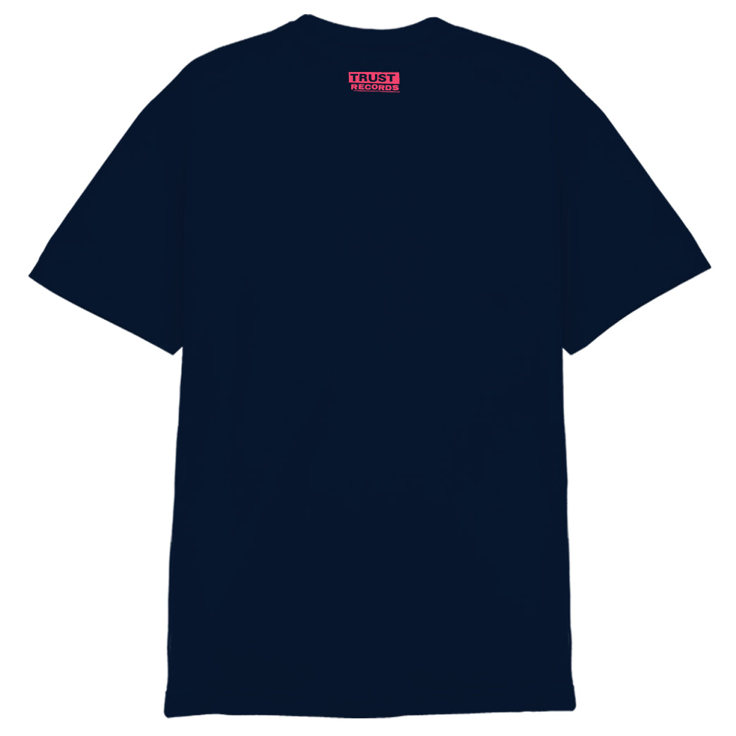 A plain navy blue 7 Seconds Alstyle 1301 t-shirt seen from the back, with a small red rectangular TRUST RECORDS label in white text near the neckline. Made from 100% cotton for comfort and durability.
