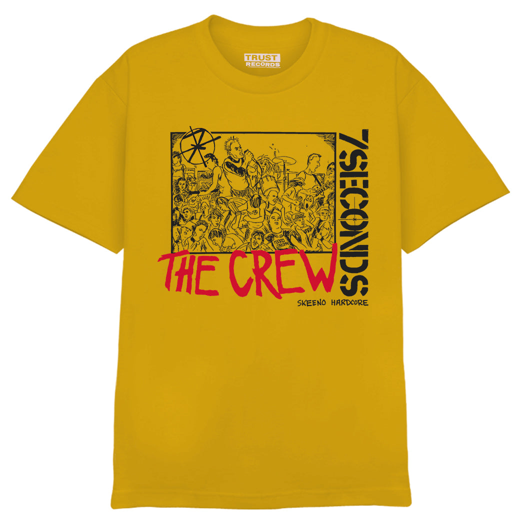 A yellow 7 Seconds Alstyle 1301 T-shirt, 100% cotton, with silkscreened black and red crowd artwork and the text 7 SECONDS, THE CREW, and SCENE/HC HARDCORE on the front. Trust Records branding is on the inside collar.