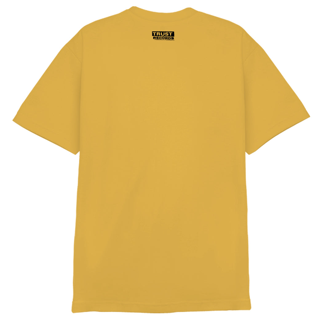 A plain yellow Better Youth Organization 1301 T-shirt shown from the back, featuring a small black and white silkscreened Trust Records label near the neckline.
