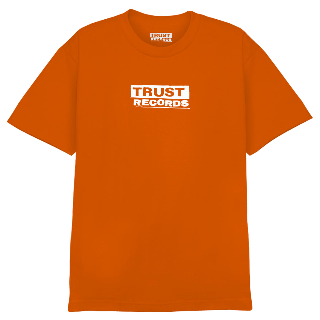 An orange Alstyle 1301 T-shirt from Trust Records with "TRUST RECORDS" boldly silkscreened in white inside a rectangle on the chest and collar. Made from 100% cotton for comfort and durability.
