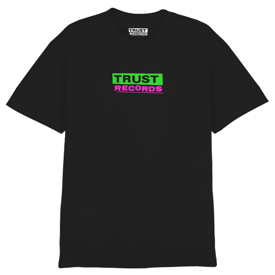 A black Trust Records 1301 Alstyle T-shirt with “TRUST” (white on green) and “RECORDS” (green on pink) silkscreened on the chest. Inside collar label reads Trust Records. Made from 100% cotton.